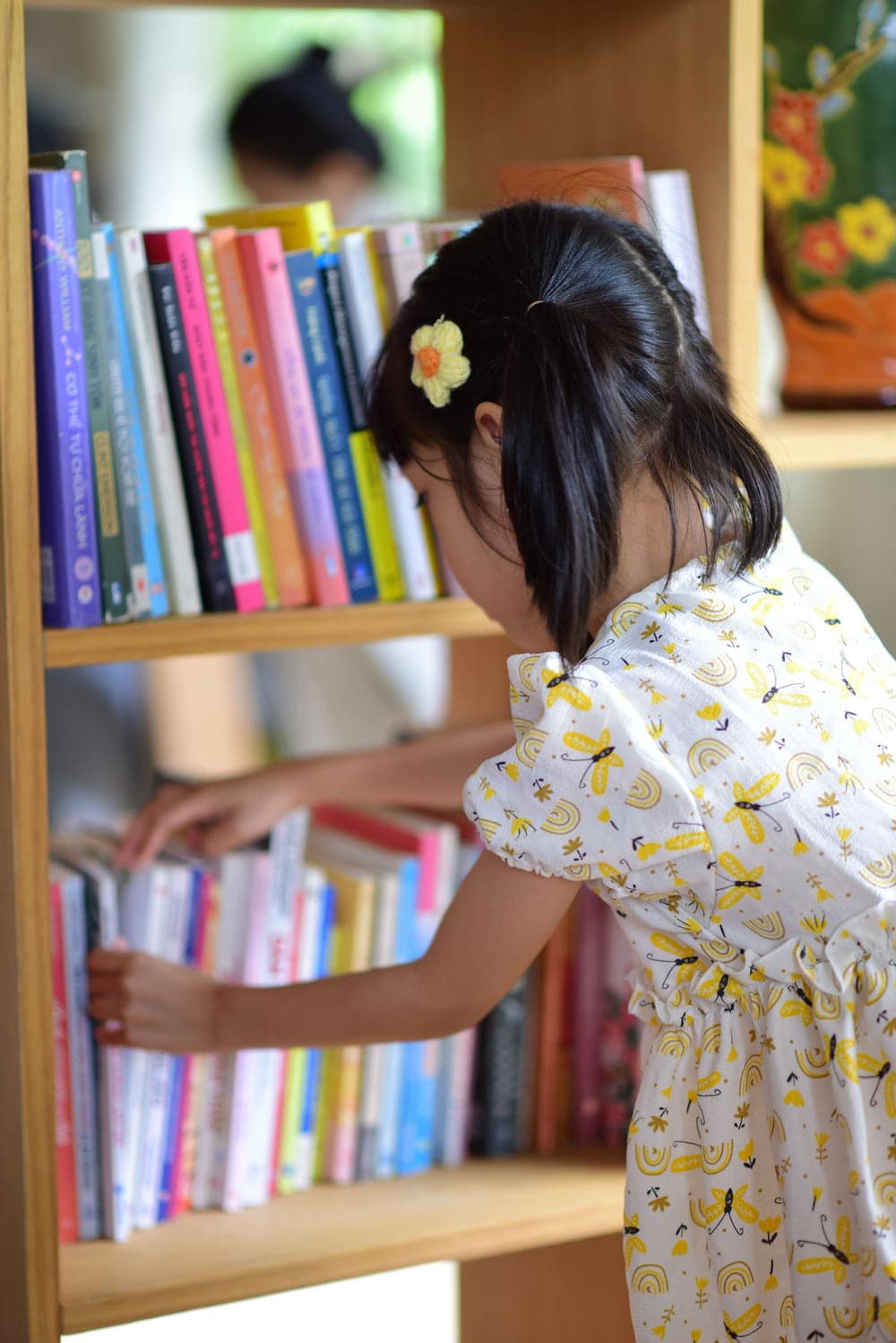 A child choosing a picture book from a low library shelf