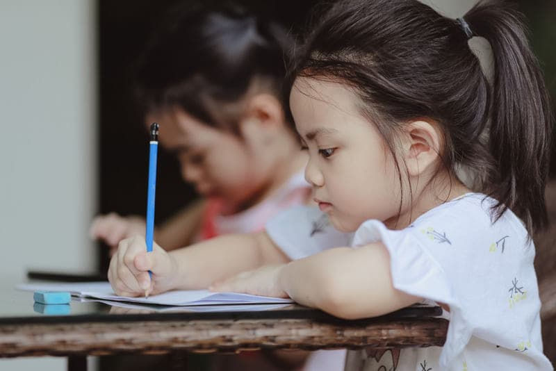 Two children concentrating on their work at a shared classroom desk