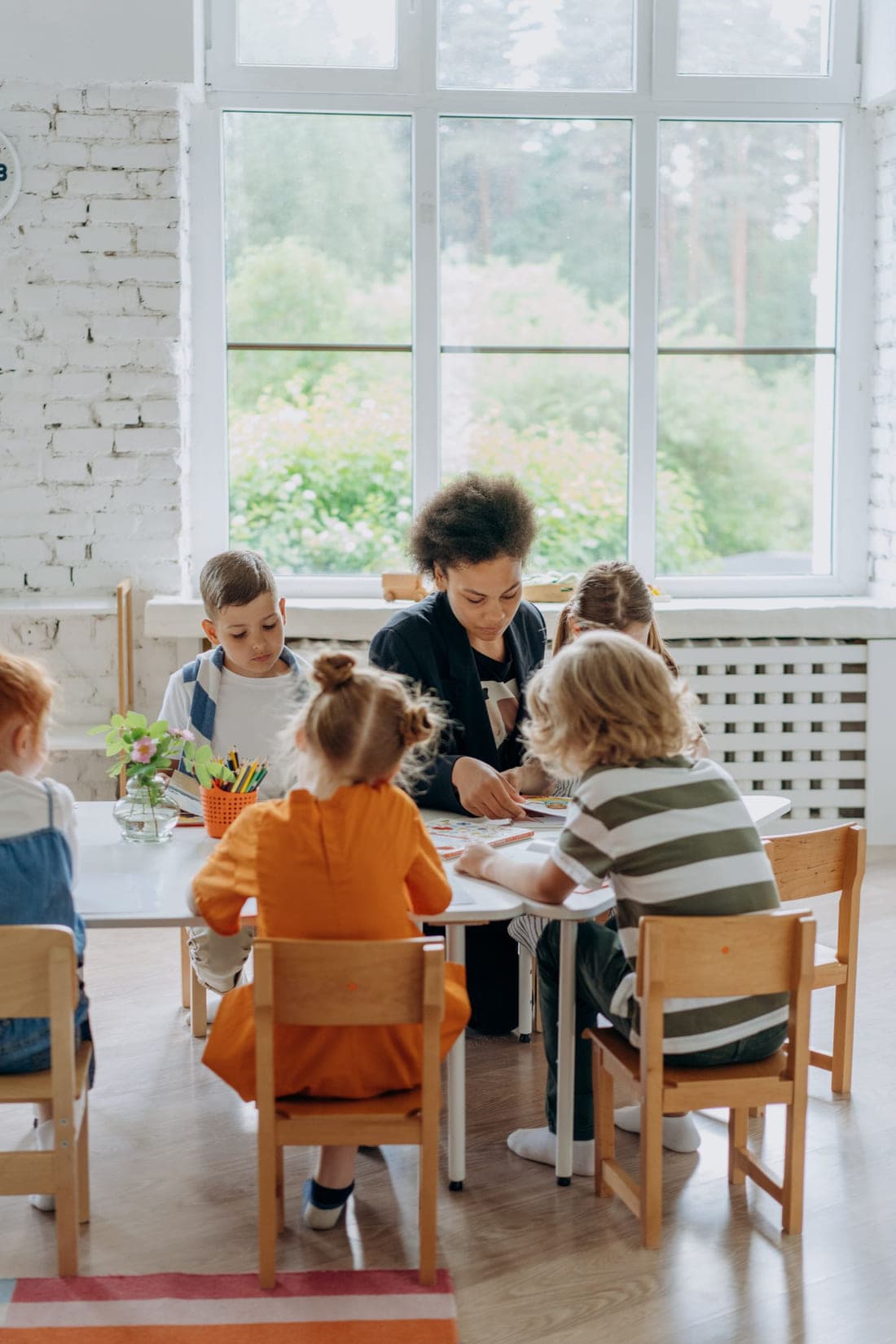 A teacher working through an activity with four children around one table