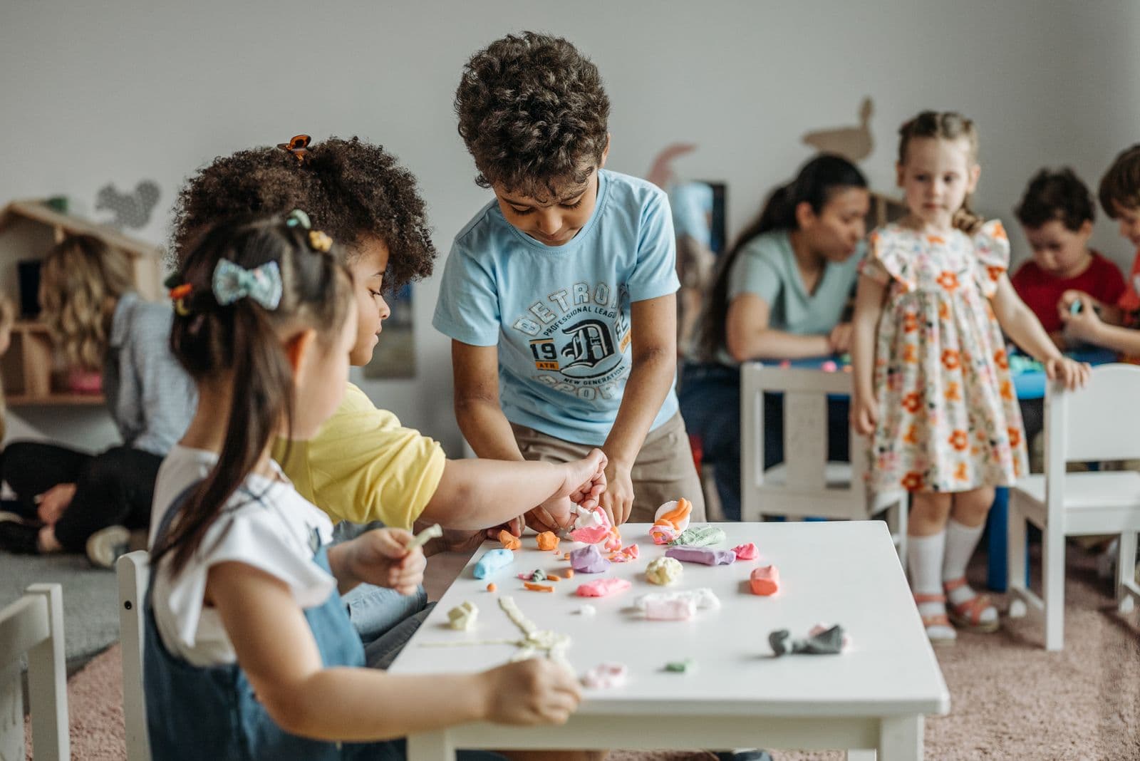 Young children working together with modelling clay at a shared table
